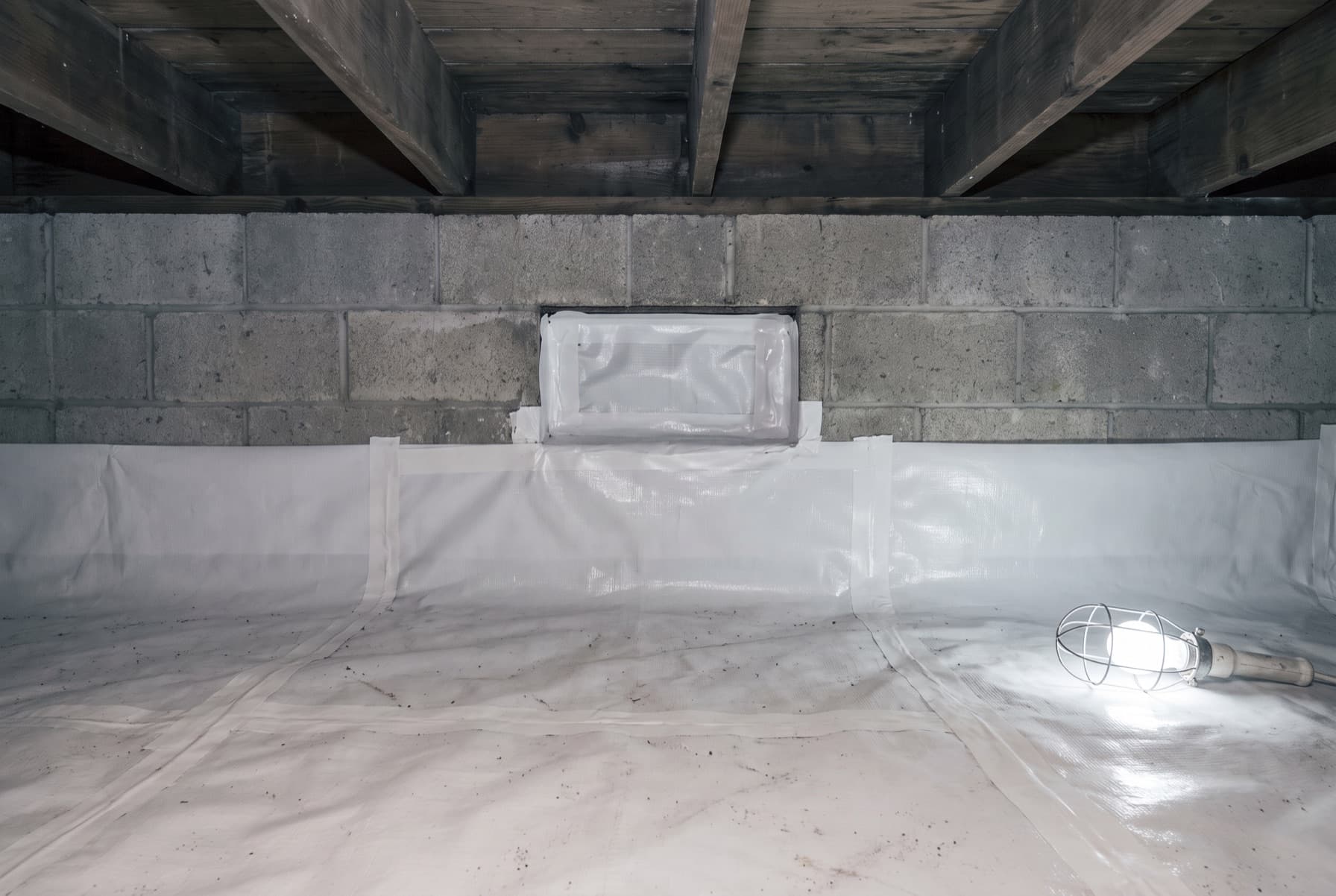 Illustration: a crawl space lined with heavy white sheeting run across the ground and up the concrete block walls, a foundation vent sealed over with taped liner, and a caged work light lying on the floor.
